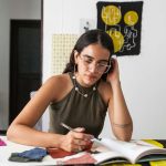 Young woman designer working thoughtfully with fabric swatches at studio.